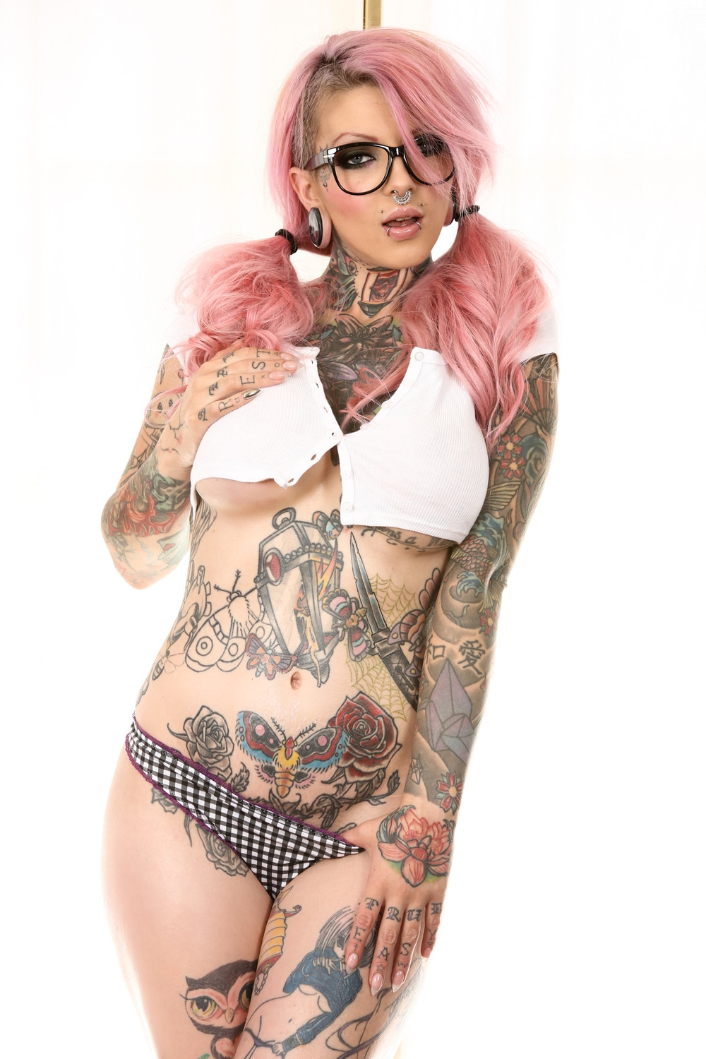 Татуированная эмо красотка с розовыми волосами и пирсингом смазливого лица Sydnee Vicious в очках позирует голышом жаркой попкой раком на полу